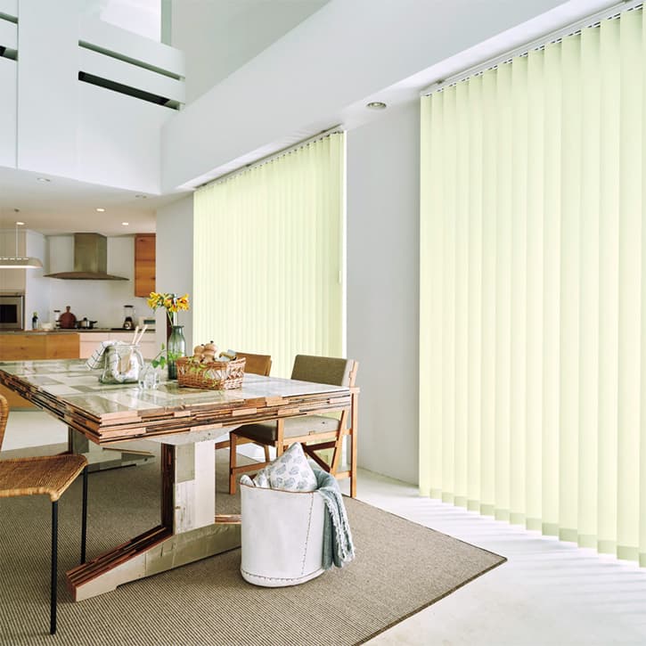 吹き抜けのリビングに設置された2台の黄緑色のバーチカルブラインド