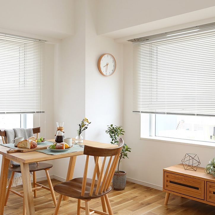 ナチュラルなリビングに設置されたホワイトのつっぱり式アルミブラインド